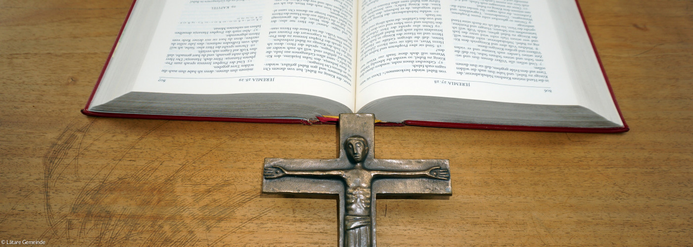 aufgeschlagene Bibel und Metallkreuz auf Altar