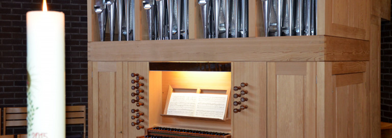 Blick auf die Orgel vom Altar aus mit Osterkerze im Vordergrund
