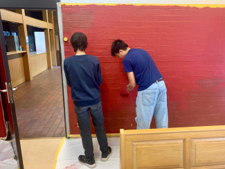 Jugendliche streichen die Wand im Jugendraum